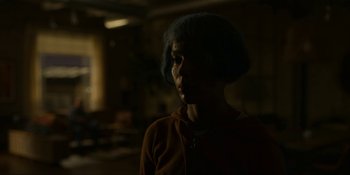 Movie still from “Kimi” (2022), directed by Steven Soderbergh – A person with short blue hair standing in a dark room; Close Up shot, Over the shoulder angle