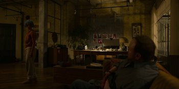 Movie still from “Kimi” (2022), directed by Steven Soderbergh – A man sitting on a couch next to a desk; Wide shot, Over the shoulder angle