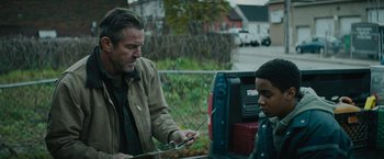 Movie still from “Kin” (2018), directed by Josh Baker – A man and a boy looking at a cell phone in front of a truck; Medium shot, Over the shoulder angle