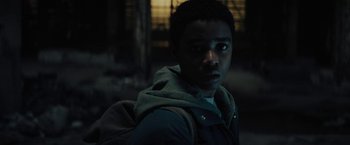 Movie still from “Kin” (2018), directed by Josh Baker – A man with a backpack standing in a dark room; Close Up shot, Low angle