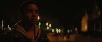 Movie still from “Kin” (2018), directed by Josh Baker – A young boy standing in front of a city street at night; Close Up shot, Low angle