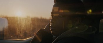 Movie still from “Kin” (2018), directed by Josh Baker – A young man looking out a window at sunset; Close Up shot, Low angle