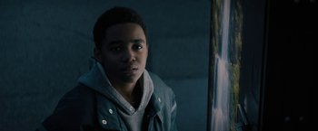 Movie still from “Kin” (2018), directed by Josh Baker – A young man is looking at the camera in the dark; Close Up shot, Over the shoulder angle