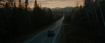 Movie still from “Kin” (2018), directed by Josh Baker – A car driving down a road near some trees; Extreme Wide shot, High angle