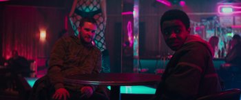 Movie still from “Kin” (2018), directed by Josh Baker – A man sitting at a table in front of a woman; Medium shot, Over the shoulder angle