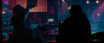 Movie still from “Kin” (2018), directed by Josh Baker – People are sitting at tables in a dark room; Medium shot, Over the shoulder angle