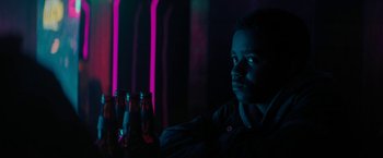 Movie still from “Kin” (2018), directed by Josh Baker – A man in a dark room with neon lights; Close Up shot, Over the shoulder angle