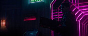 Movie still from “Kin” (2018), directed by Josh Baker – A person holding a remote control in a room lit up with neon lights; Medium shot, Low angle