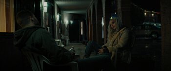Movie still from “Kin” (2018), directed by Josh Baker – A woman sitting on a chair in a dark room; Medium shot, High angle