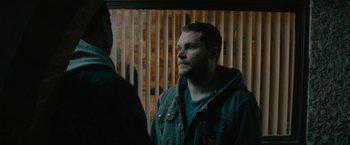 Movie still from “Kin” (2018), directed by Josh Baker – A man with a beard talking to another man in front of a wooden wall; Close Up shot, Over the shoulder angle