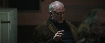 Movie still from “Kin” (2018), directed by Josh Baker – An older man in a brown jacket is pointing; Close Up shot, Over the shoulder angle