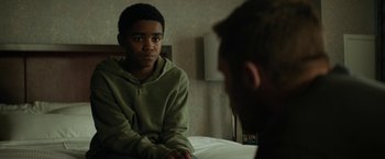 Movie still from “Kin” (2018), directed by Josh Baker – A young man sitting in front of another man in a room; Close Up shot, Over the shoulder angle