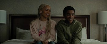 Movie still from “Kin” (2018), directed by Josh Baker – Two young people sitting on a bed smiling for the camera; Medium shot, Over the shoulder angle