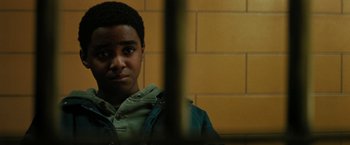 Movie still from “Kin” (2018), directed by Josh Baker – A young man looking out of a jail cell window; Close Up shot, Over the shoulder angle