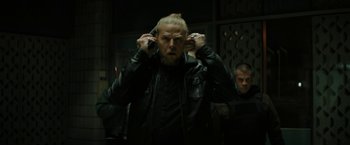 Movie still from “Kin” (2018), directed by Josh Baker – A man in a leather jacket is talking on a cell phone; Close Up shot, Over the shoulder angle