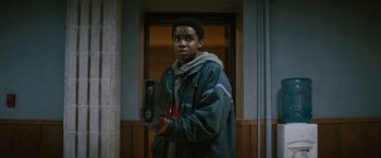 Movie still from “Kin” (2018), directed by Josh Baker – A young man holding a piece of wood in his hand; Medium shot, Low angle