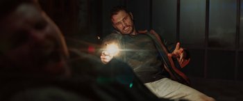 Movie still from “Kin” (2018), directed by Josh Baker – A man holding a light in his hand; Medium shot, Low angle