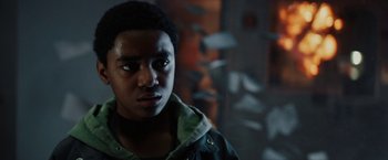 Movie still from “Kin” (2018), directed by Josh Baker – A young man in a green jacket looking at the camera; Close Up shot, Low angle