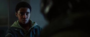 Movie still from “Kin” (2018), directed by Josh Baker – A young man in a blue jacket is looking at the camera; Close Up shot, Over the shoulder angle