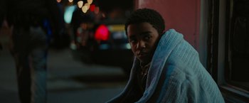 Movie still from “Kin” (2018), directed by Josh Baker – A young man wrapped in a blanket looks at the camera; Close Up shot, High angle