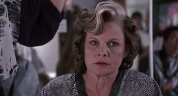 Movie still from “Kindergarten Cop” (1990), directed by Ivan Reitman – An older woman with a frowning look on her face; Close Up shot, Over the shoulder angle