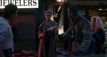 Movie still from “Kindergarten Cop” (1990), directed by Ivan Reitman – Two men are standing in the dark holding guns; Wide shot, Low angle