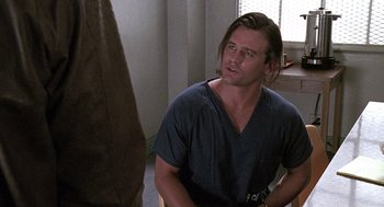 Movie still from “Kindergarten Cop” (1990), directed by Ivan Reitman – A man sitting in front of a window in a room; Close Up shot, Over the shoulder angle