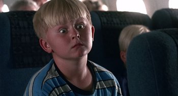 Movie still from “Kindergarten Cop” (1990), directed by Ivan Reitman – A young boy sitting on a seat on an airplane; Close Up shot, High angle