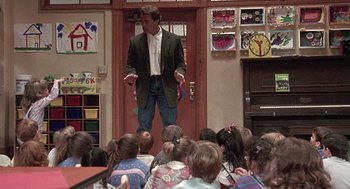Movie still from “Kindergarten Cop” (1990), directed by Ivan Reitman – A man standing in front of a group of children; Wide shot, High angle
