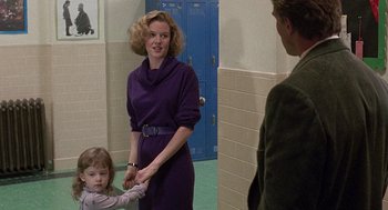 Movie still from “Kindergarten Cop” (1990), directed by Ivan Reitman – A woman in a purple dress holding a child's hand in front of a man; Medium shot, Over the shoulder angle