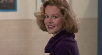 Movie still from “Kindergarten Cop” (1990), directed by Ivan Reitman – A young woman in a purple sweater smiling for the camera; Close Up shot, Over the shoulder angle