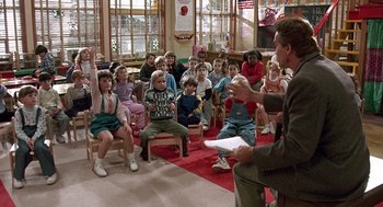 Movie still from “Kindergarten Cop” (1990), directed by Ivan Reitman – A group of children sitting in front of an adult; Wide shot, High angle