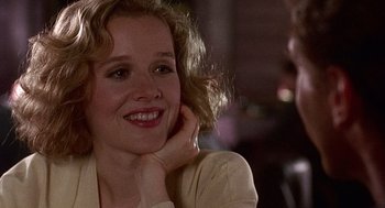 Movie still from “Kindergarten Cop” (1990), directed by Ivan Reitman – A person smiling with her hand under her chin; Close Up shot, Over the shoulder angle