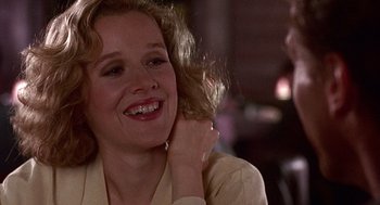 Movie still from “Kindergarten Cop” (1990), directed by Ivan Reitman – A person smiling with her hand in her hair; Close Up shot, Over the shoulder angle