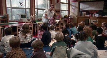Movie still from “Kindergarten Cop” (1990), directed by Ivan Reitman – A group of children sitting in a room with an adult reading; Wide shot, High angle