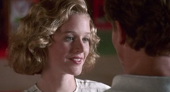 Movie still from “Kindergarten Cop” (1990), directed by Ivan Reitman – A young woman smiles at the camera as a young man looks on; Close Up shot, Over the shoulder angle