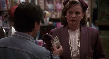 Movie still from “Kindergarten Cop” (1990), directed by Ivan Reitman – An older woman is holding a wallet while a younger woman looks on; Close Up shot, Over the shoulder angle