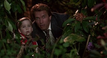 Movie still from “Kindergarten Cop” (1990), directed by Ivan Reitman – A man and a boy in a suit and tie looking at the camera; Close Up shot, Low angle