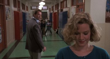 Movie still from “Kindergarten Cop” (1990), directed by Ivan Reitman – A man and a woman are walking down a hallway; Medium shot, Over the shoulder angle