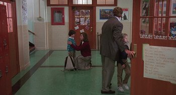 Movie still from “Kindergarten Cop” (1990), directed by Ivan Reitman – A woman sitting on the ground with a child; Wide shot, Over the shoulder angle