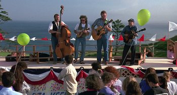 Movie still from “Kindergarten Cop” (1990), directed by Ivan Reitman – A group of people playing music on a stage; Wide shot, Low angle