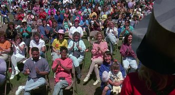 Movie still from “Kindergarten Cop” (1990), directed by Ivan Reitman – A group of people sitting in chairs in the grass; Medium shot, Over the shoulder angle