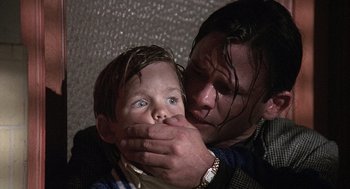 Movie still from “Kindergarten Cop” (1990), directed by Ivan Reitman – A young boy covering his mouth with his hands; Close Up shot, Over the shoulder angle