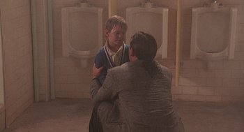 Movie still from “Kindergarten Cop” (1990), directed by Ivan Reitman – A man and a boy are in a bathroom; Medium shot, Over the shoulder angle