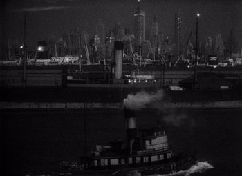 Movie still from “King Kong” (1933), directed by Merian C. Cooper – A tug boat in the water at night with a city skyline in the background; Extreme Wide shot, High angle