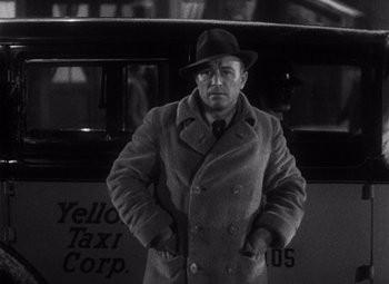 Movie still from “King Kong” (1933), directed by Merian C. Cooper – A black and white photo of a man in a hat and coat; Medium shot, Low angle