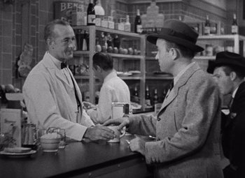Movie still from “King Kong” (1933), directed by Merian C. Cooper – Two men at a bar talking to each other; Medium shot, Over the shoulder angle