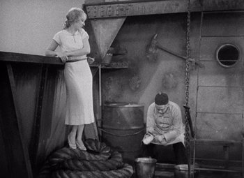 Movie still from “King Kong” (1933), directed by Merian C. Cooper – An old photo of a man and a woman cooking food; Wide shot, High angle