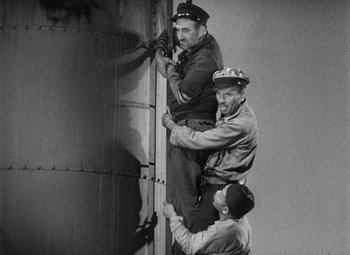 Movie still from “King Kong” (1933), directed by Merian C. Cooper – A group of men hanging on to the side of a building; Medium shot, Low angle