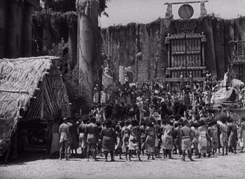 Movie still from “King Kong” (1933), directed by Merian C. Cooper – A group of people standing in front of a building; Extreme Wide shot, High angle
